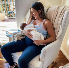 A person in a white armchair feeding a newborn baby, as Coach Cat discusses moderate intensity.